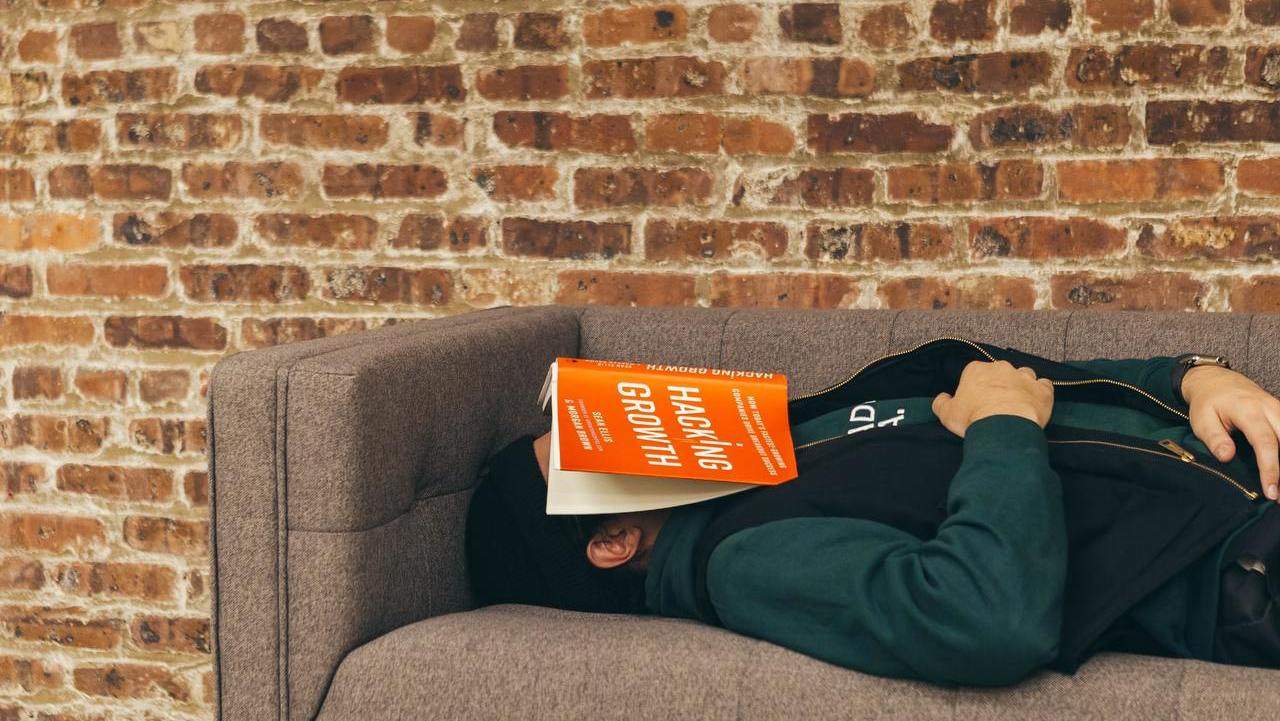 Man asleep on sofa with book on his face